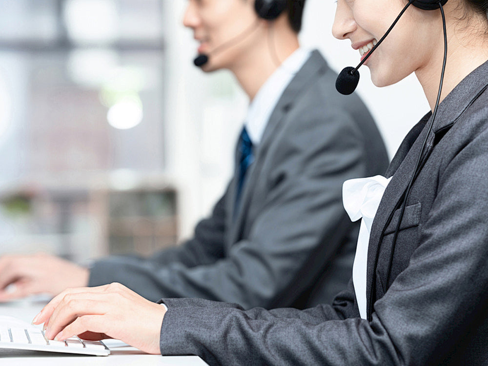 Two call center agents wearing headsets and working on computers.